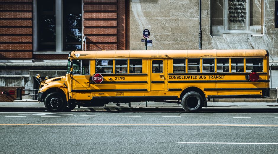 A charter bus parked next to a yellow school bus, comparing group transportation options