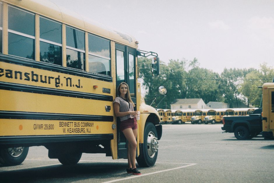A charter bus parked outside a venue during a busy weekend event with guests boarding