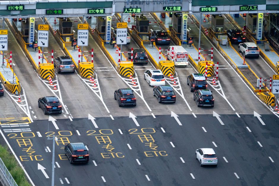 Cars and a bus passing through a highway toll booth to pay road tolls