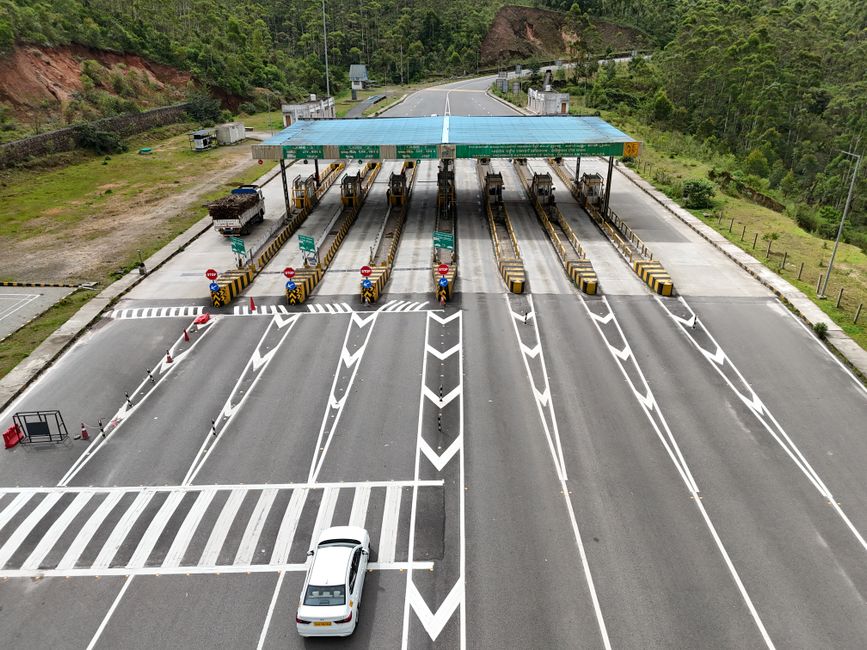 Charter bus driving through a highway toll booth on a busy road