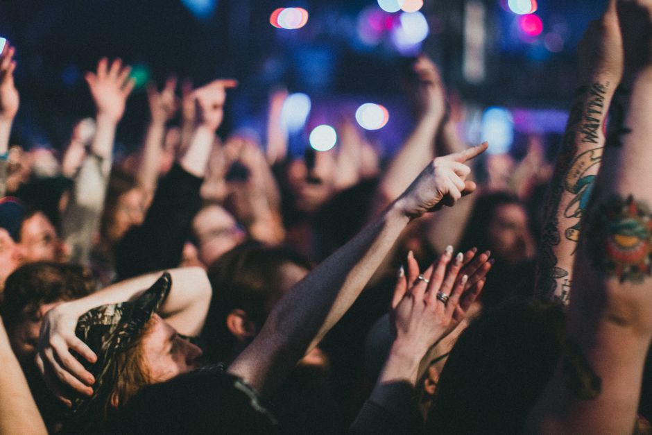 Charter bus parked near a music festival venue with attendees boarding for group travel