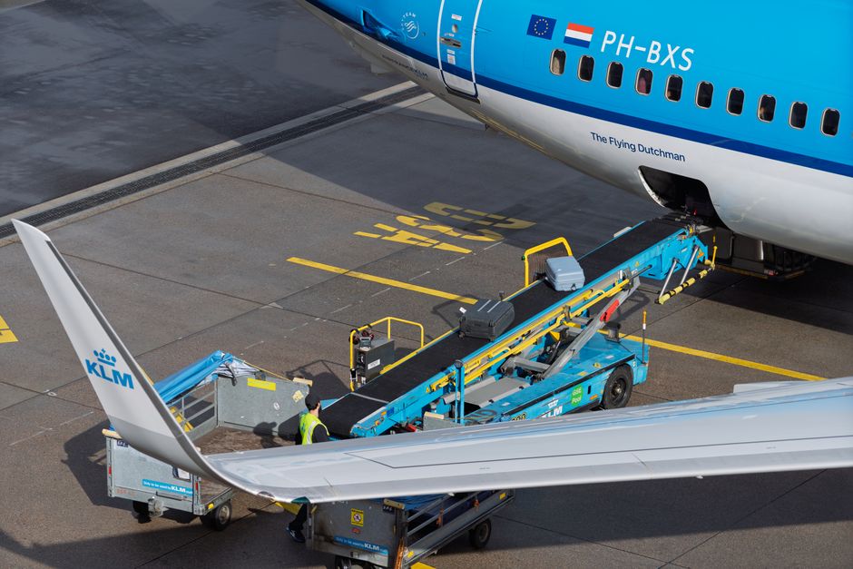 Charter bus with passengers loading luggage into the cargo bay before departure