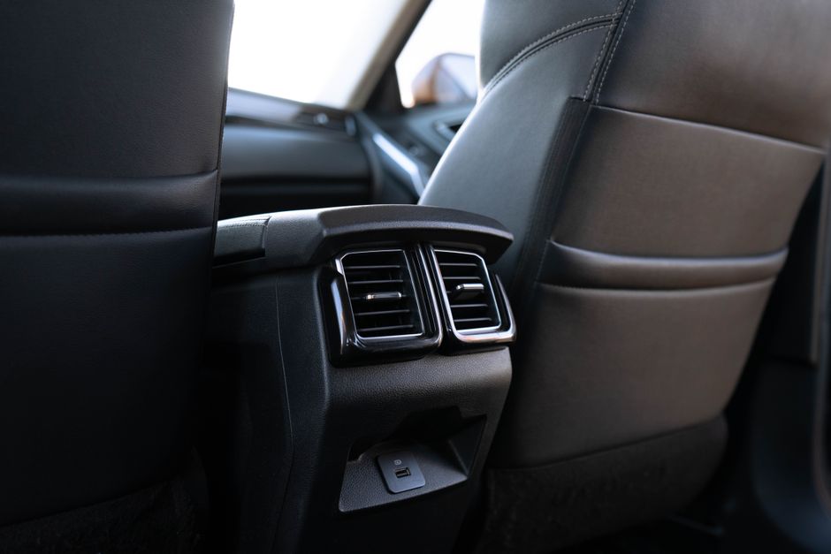 Interior view of a charter bus showing air conditioning vents above passenger seats