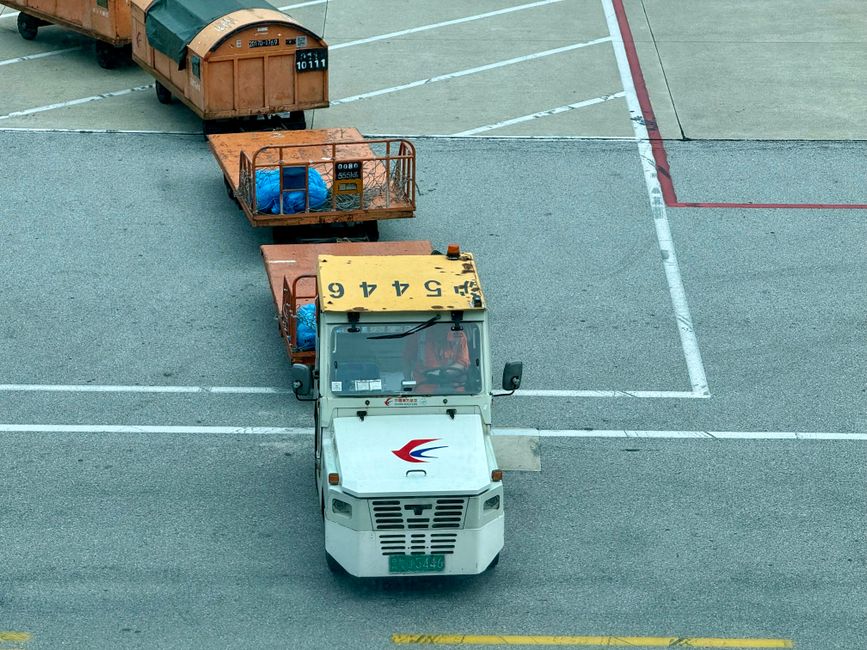 Passengers loading labeled luggage into the cargo hold of a charter bus before a group trip