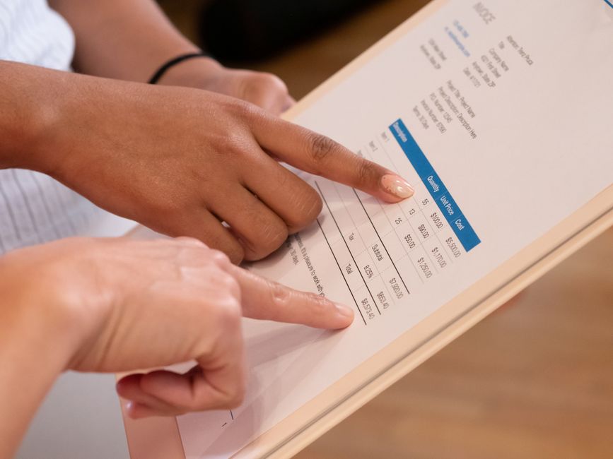 Person reviewing an itemized charter bus quote on a clipboard next to a parked coach bus