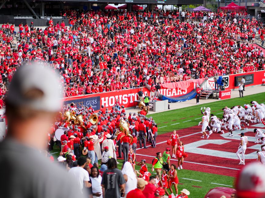 Group of college football fans tailgating in a stadium parking lot before a bowl game