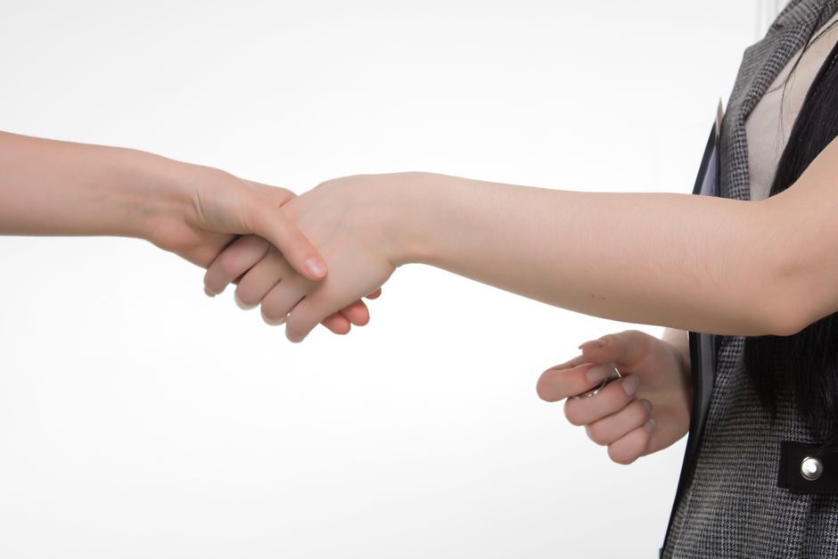 Two people shaking hands in front of a charter bus after negotiating a better price