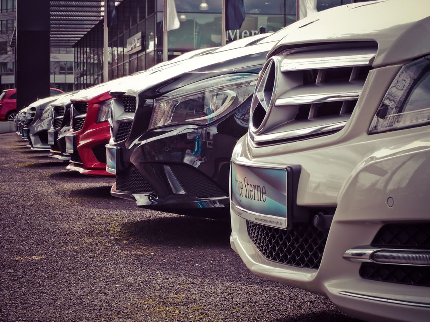 A charter bus parked beside a row of rental cars, comparing group travel options